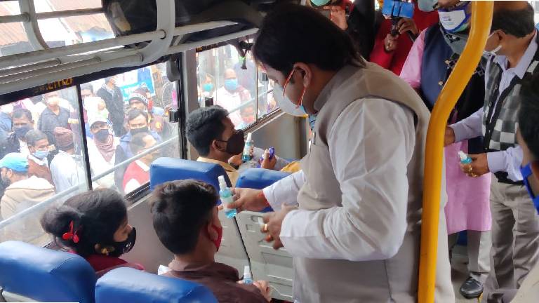 nominated member of the Regional Transport Office Priyangu Pandey giving masks and sanitizers to the bus passengers